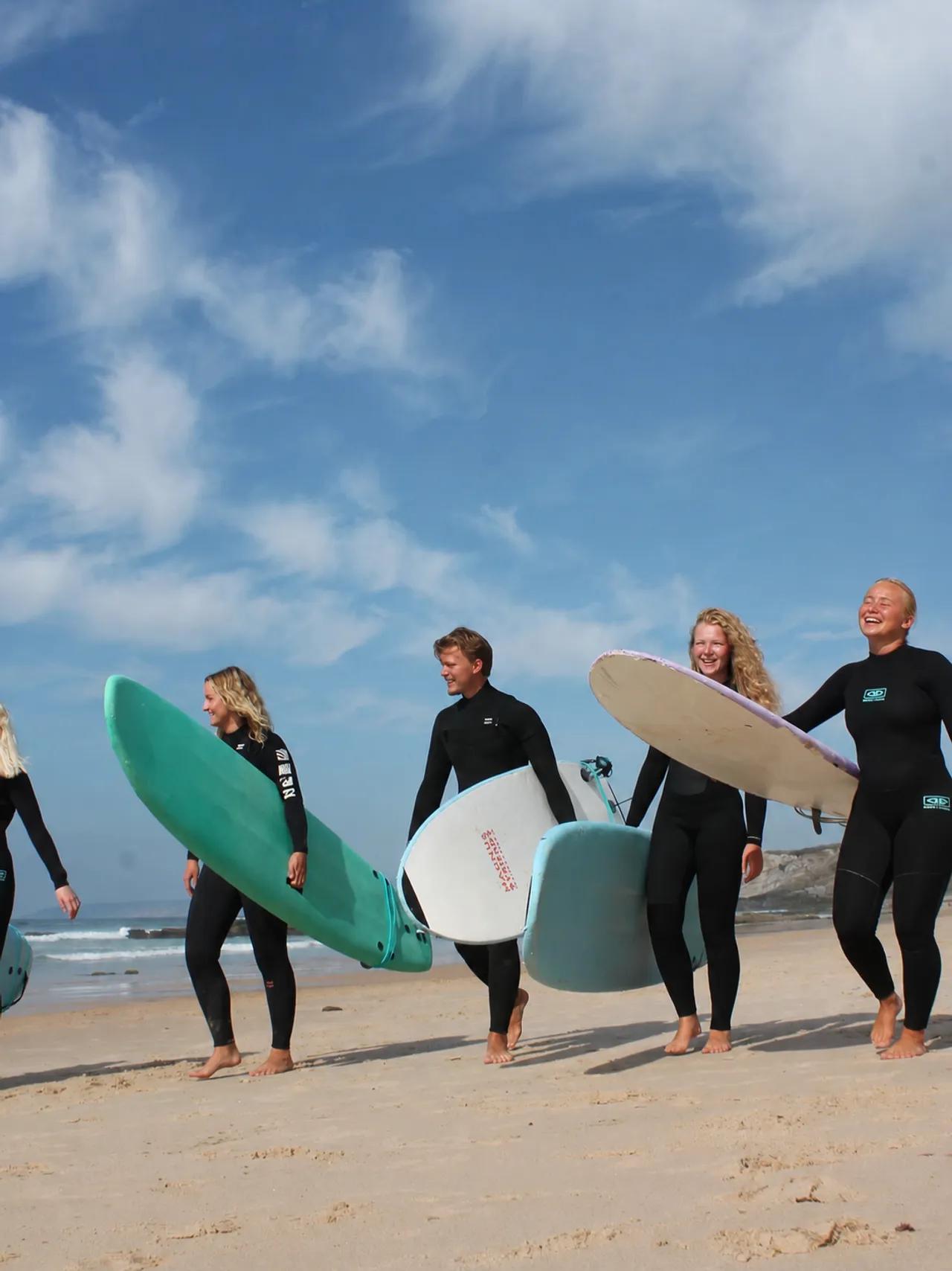 Surfmedarbetare på stranden med brädor påväg till surf