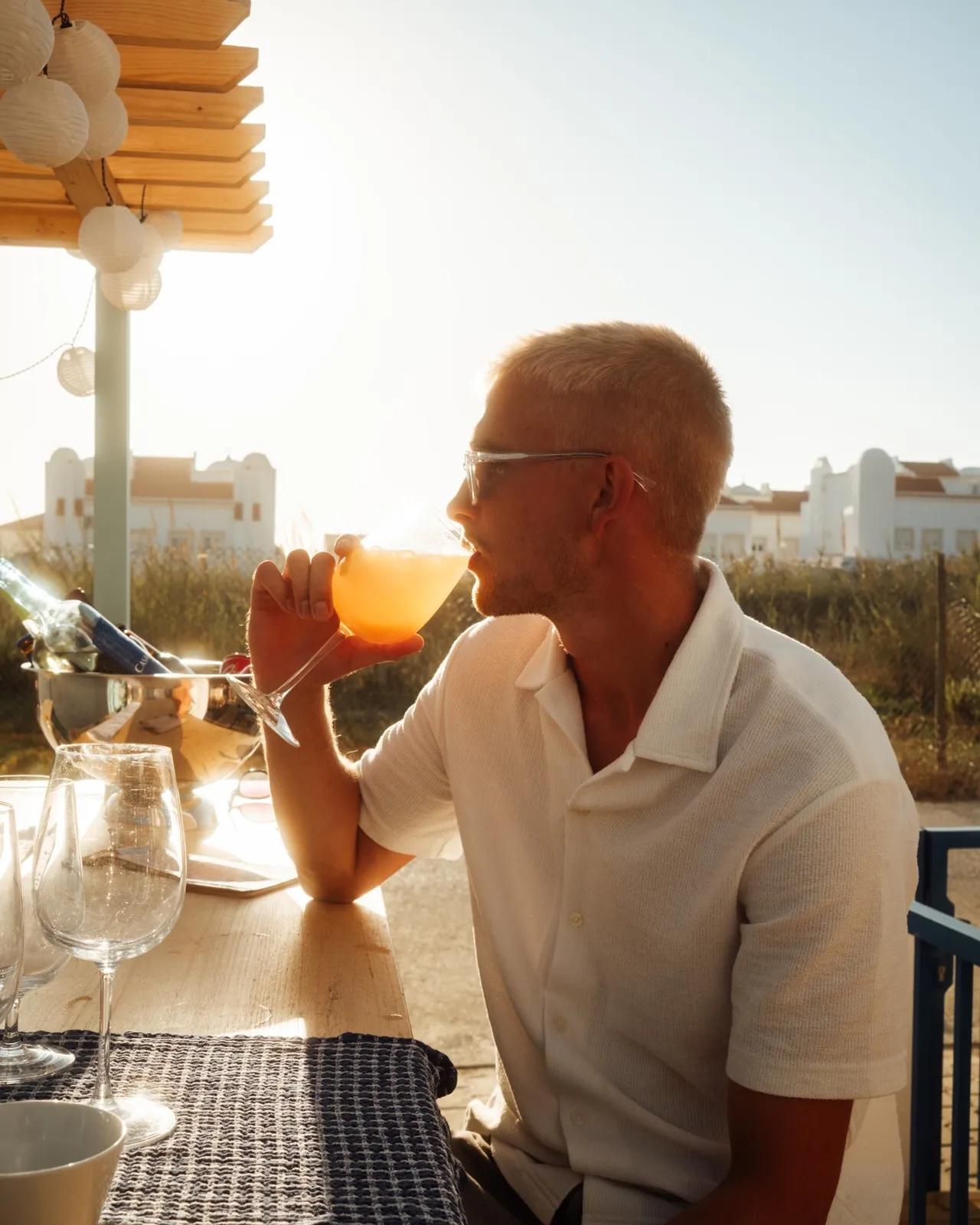 Man dricker drink i solnedgången på after surf