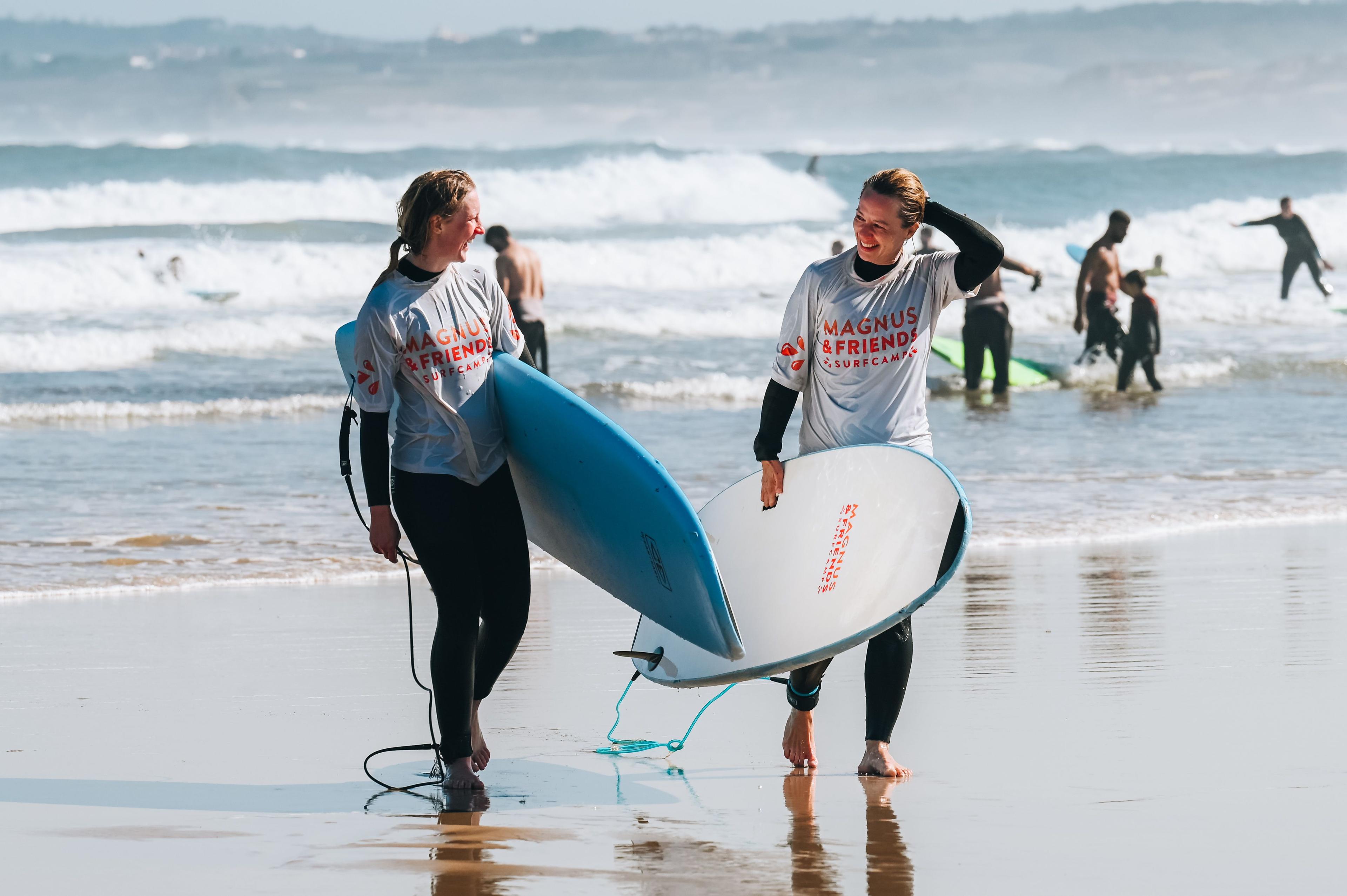 Två glada tjejer med surfbrädor