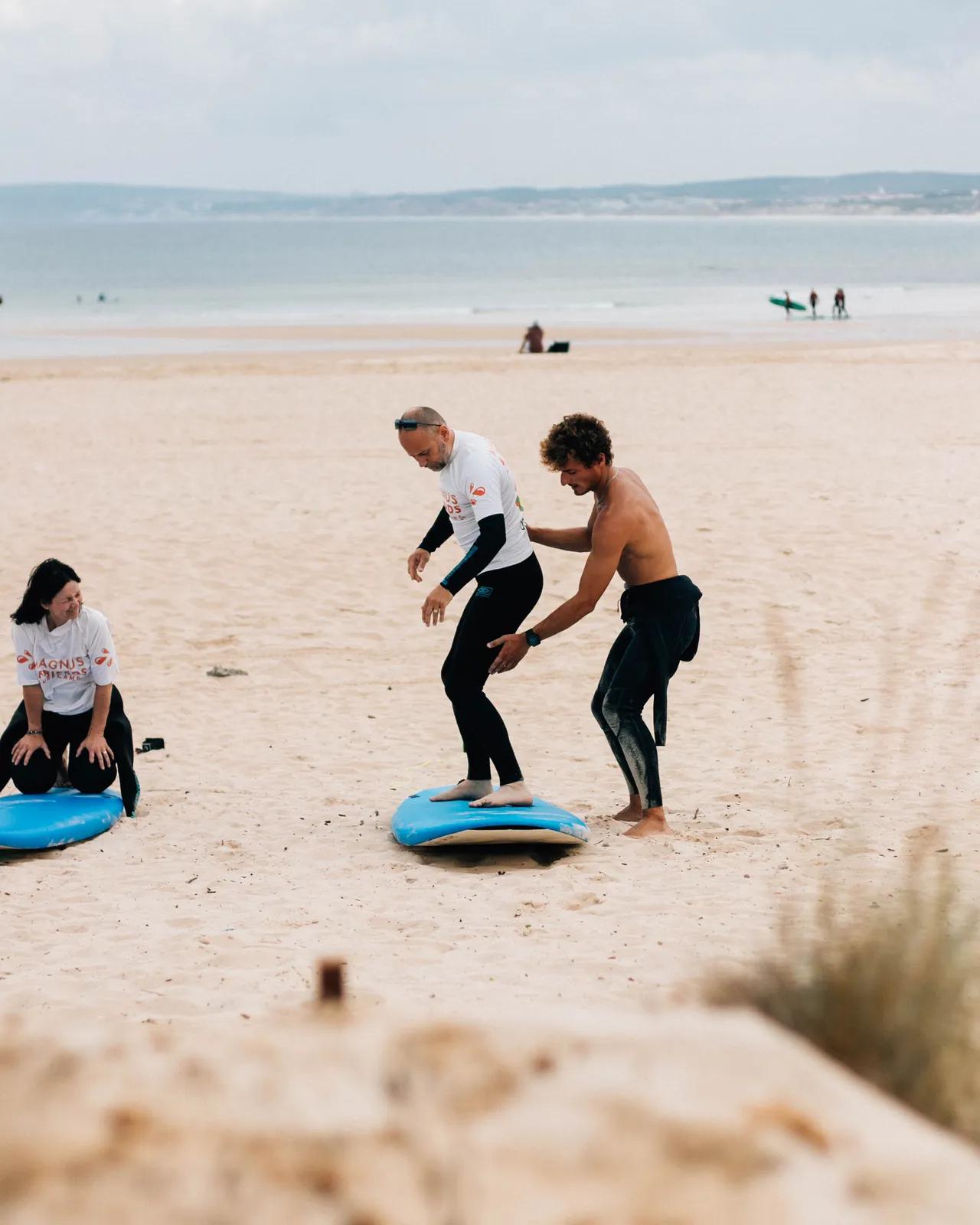 Surfare med instruktör under en lektion på stranden