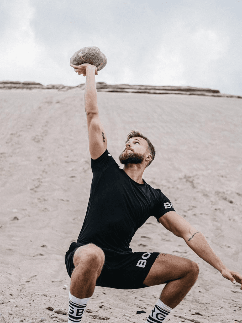 Måns Cederberg lyfter sten på stranden