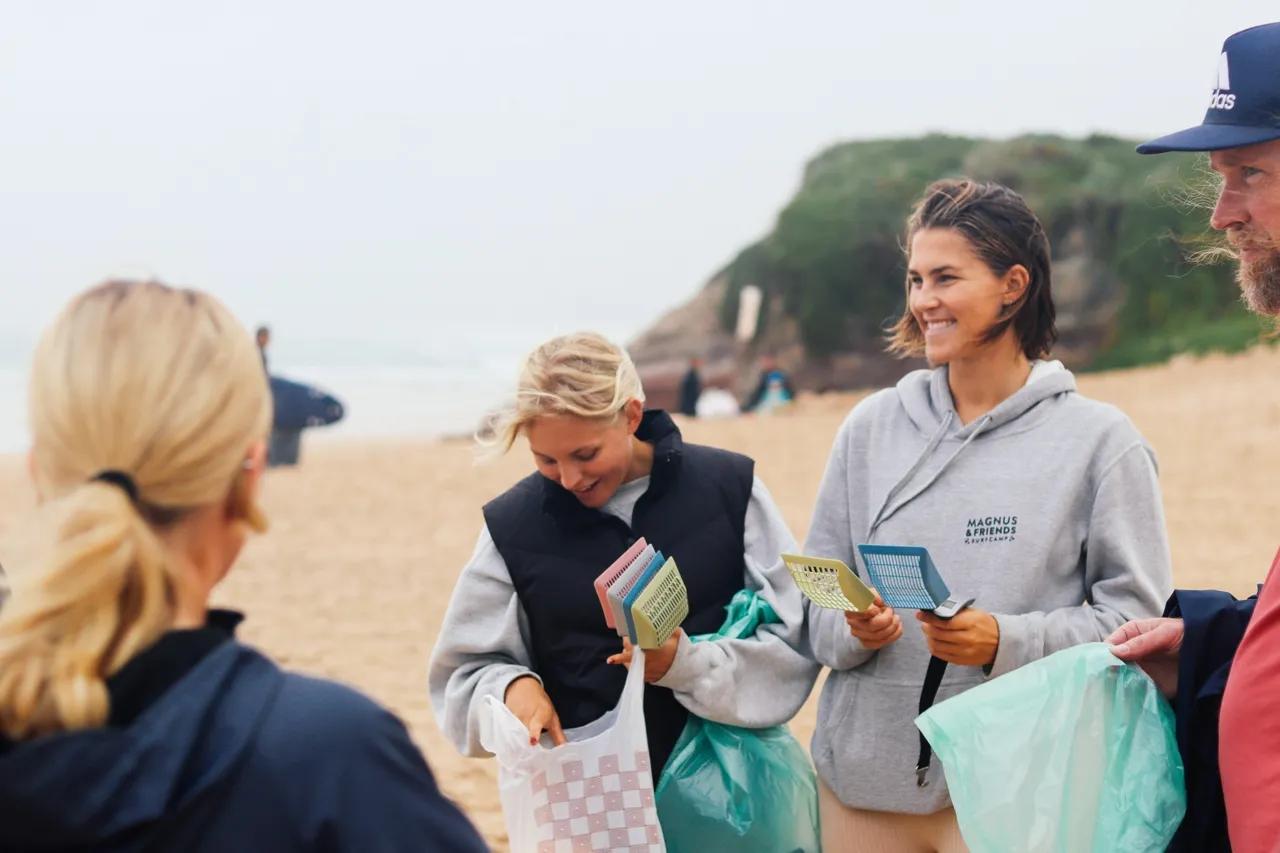 Tjejer på strande som plockar upp skräp och gör stranden ren och fin