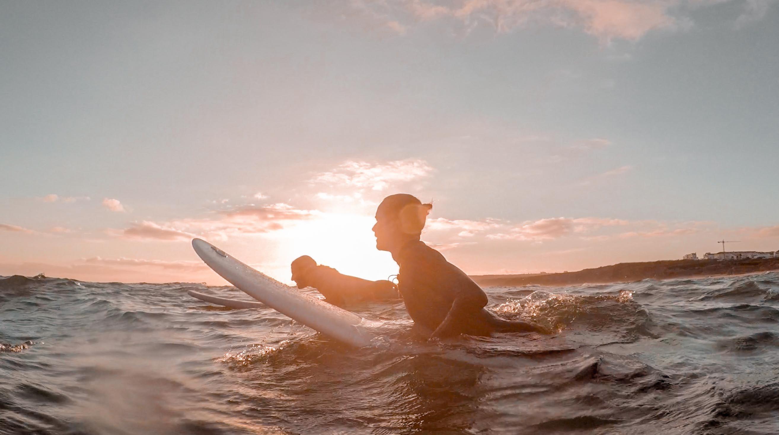 Magnus och Mohammed som surfar i solnedgången