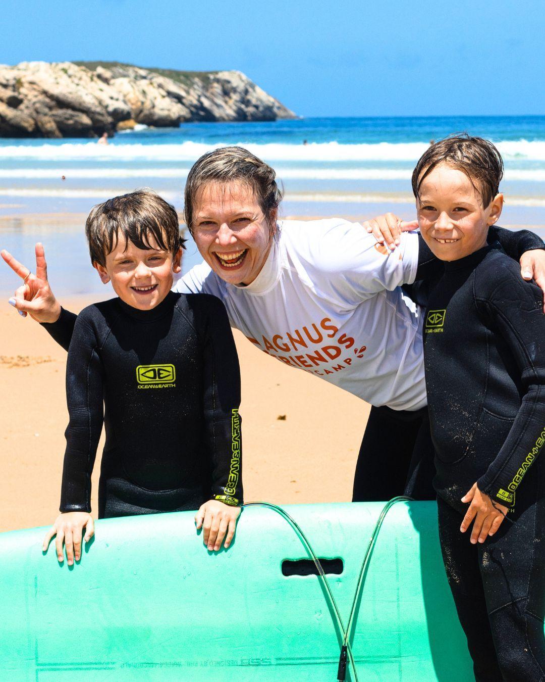 En vuxen surfare och två små surfare, glada efter surflektion