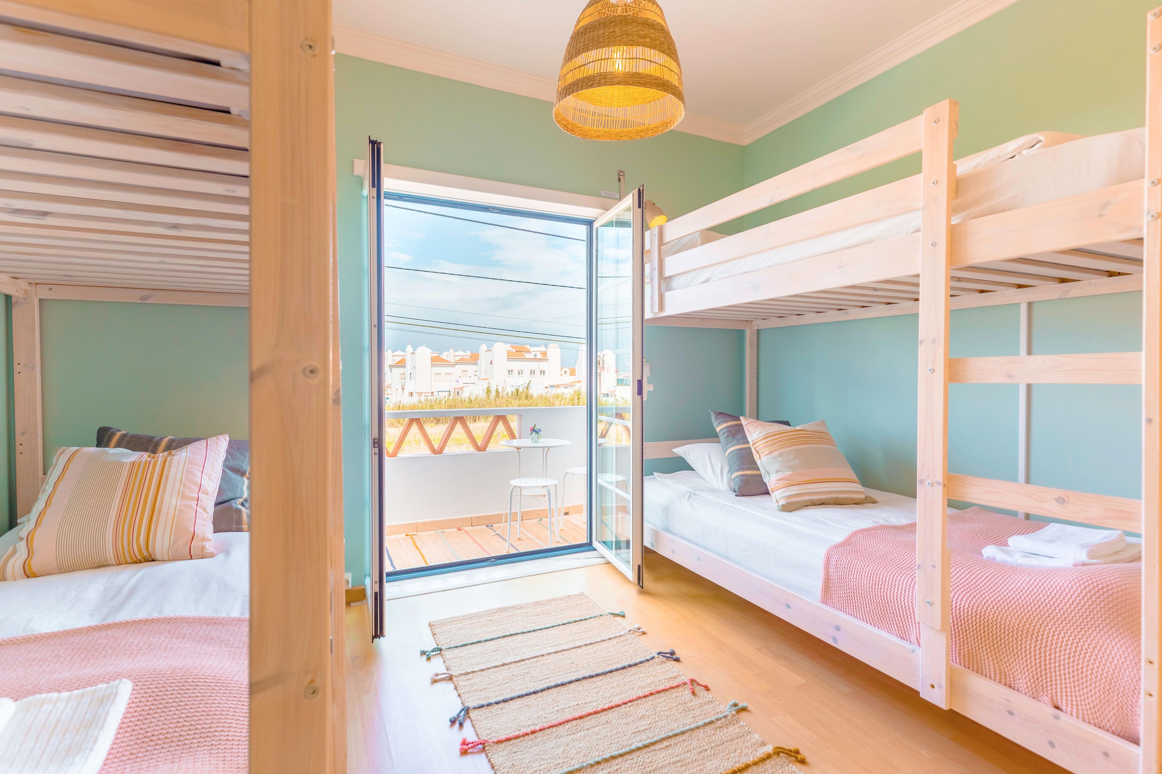 Flerbäddsrum med våningssängar och balkong i ljusa färger