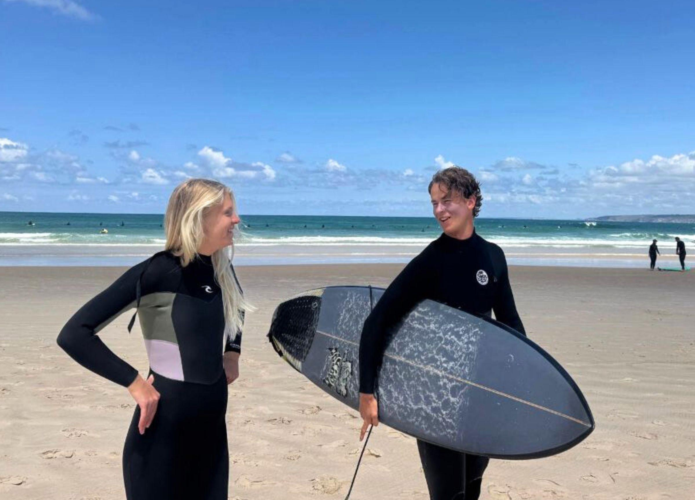 Två medarbetare på Magnus & friends surfcamp som skrattar tillsammans på stranden efter en surfsession