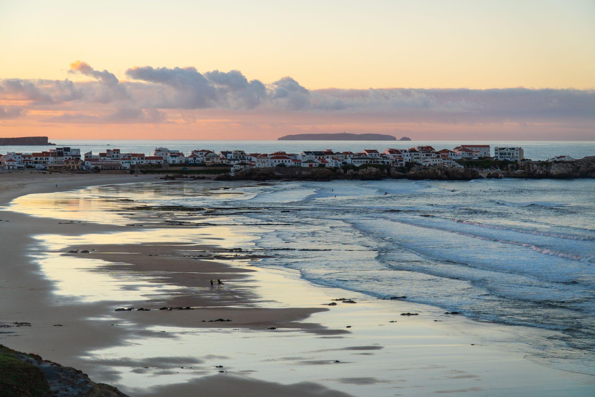 Vy över en strand i solnedgång med små vågor som rullar in mot land
