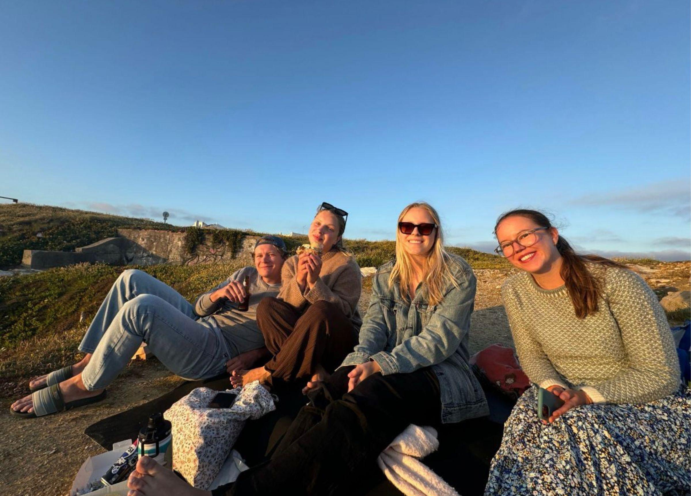 Fyra medarbetare från Magnus & friends njuter av solnedgången tillsammans vid klipporna