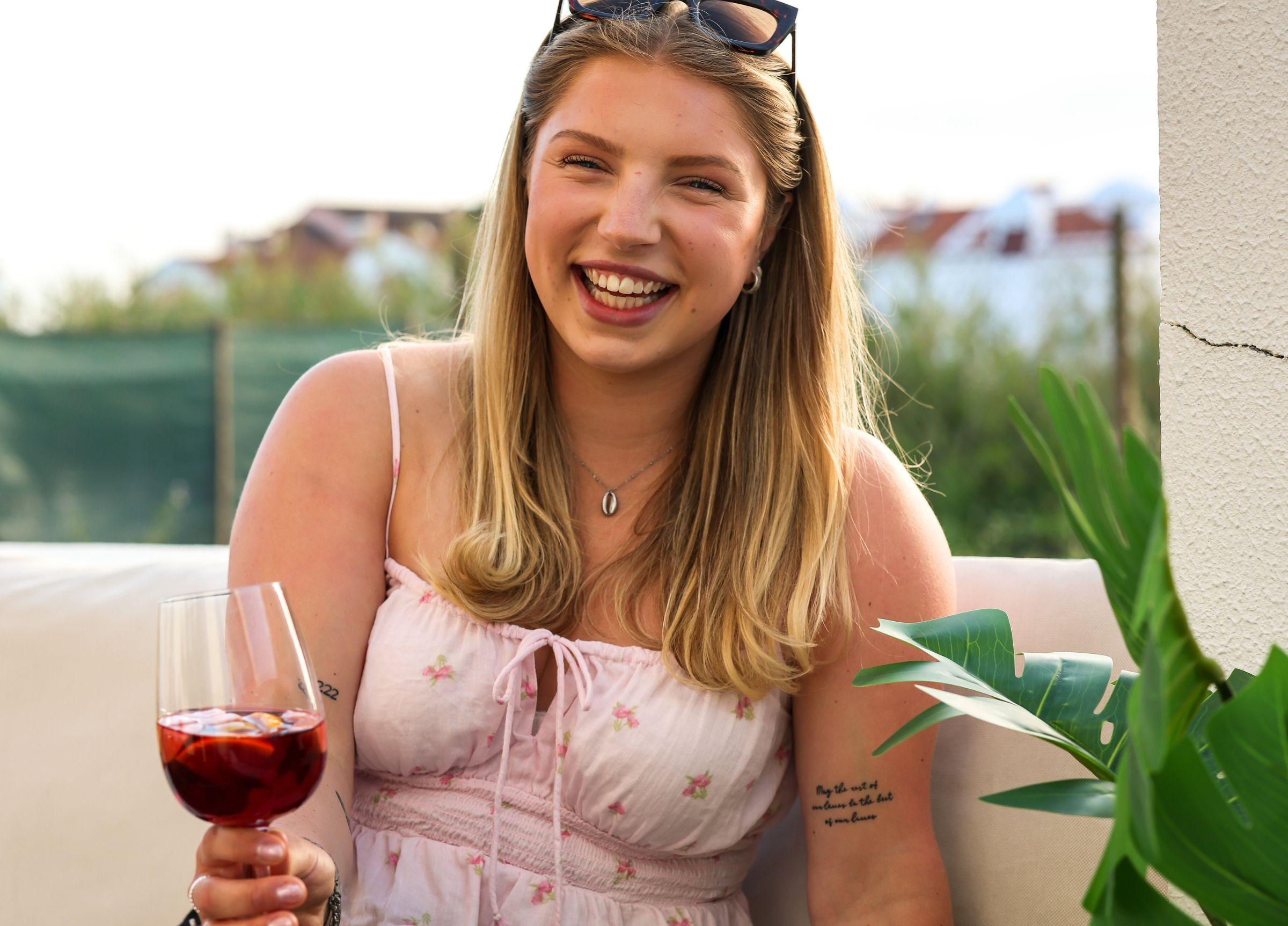 Skrattandes tjej på middag hos Magnus & friends med ett glas vin i handen