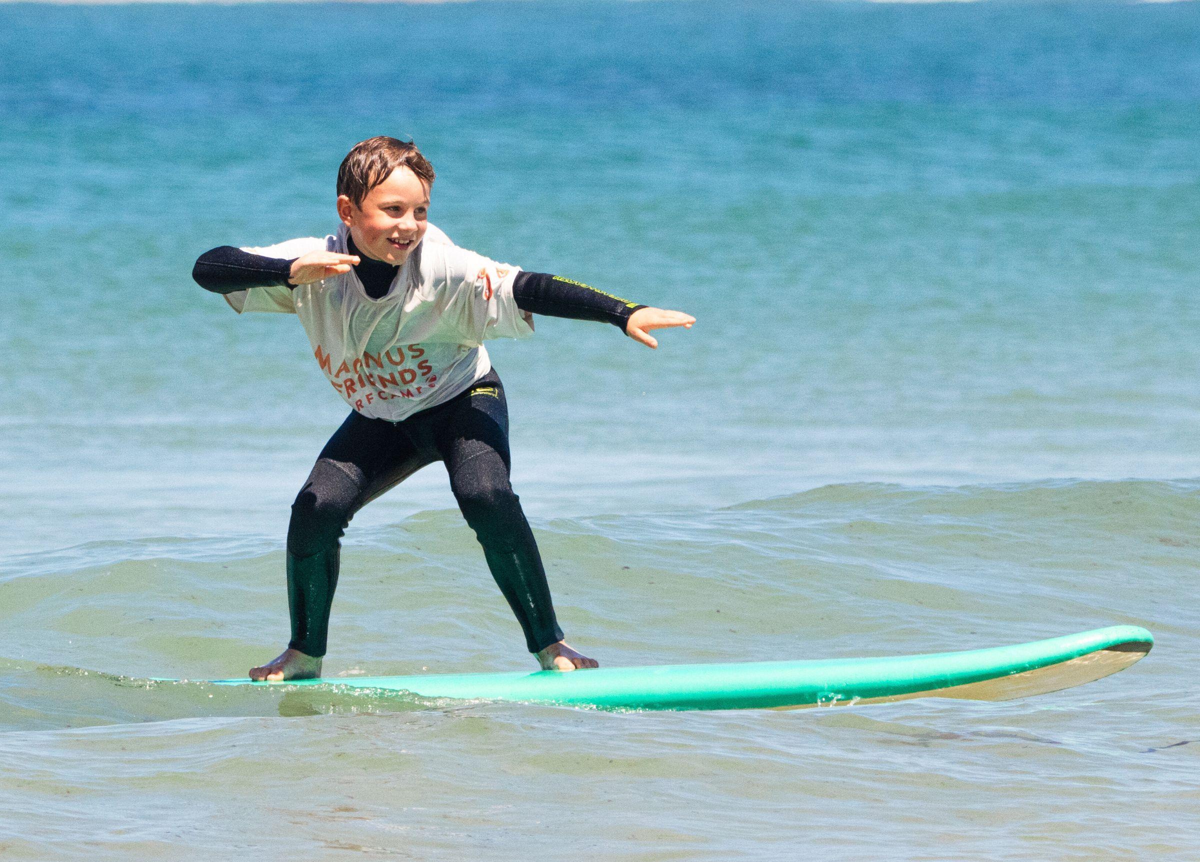 En ung kille som surfar en våg och är glad