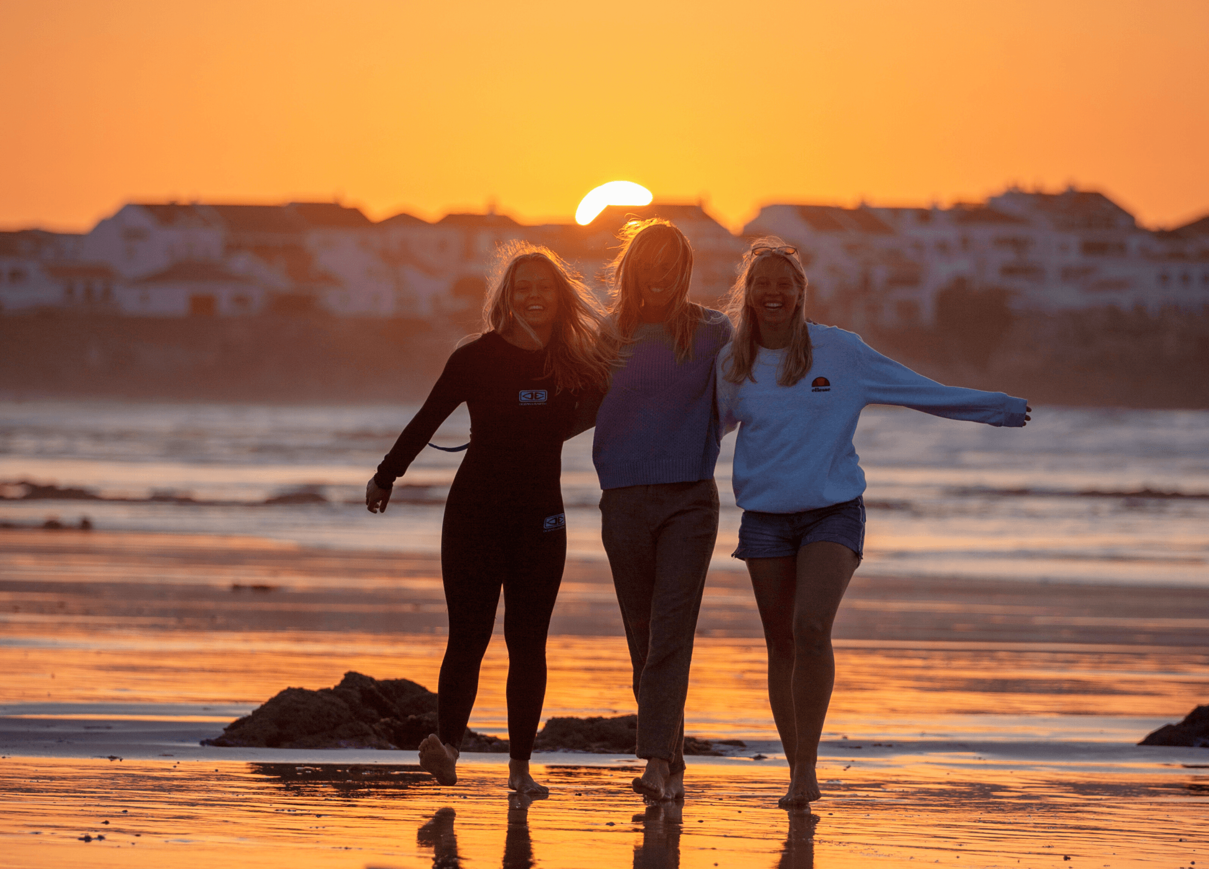 Tre glada kompisar på stranden under solnedgången