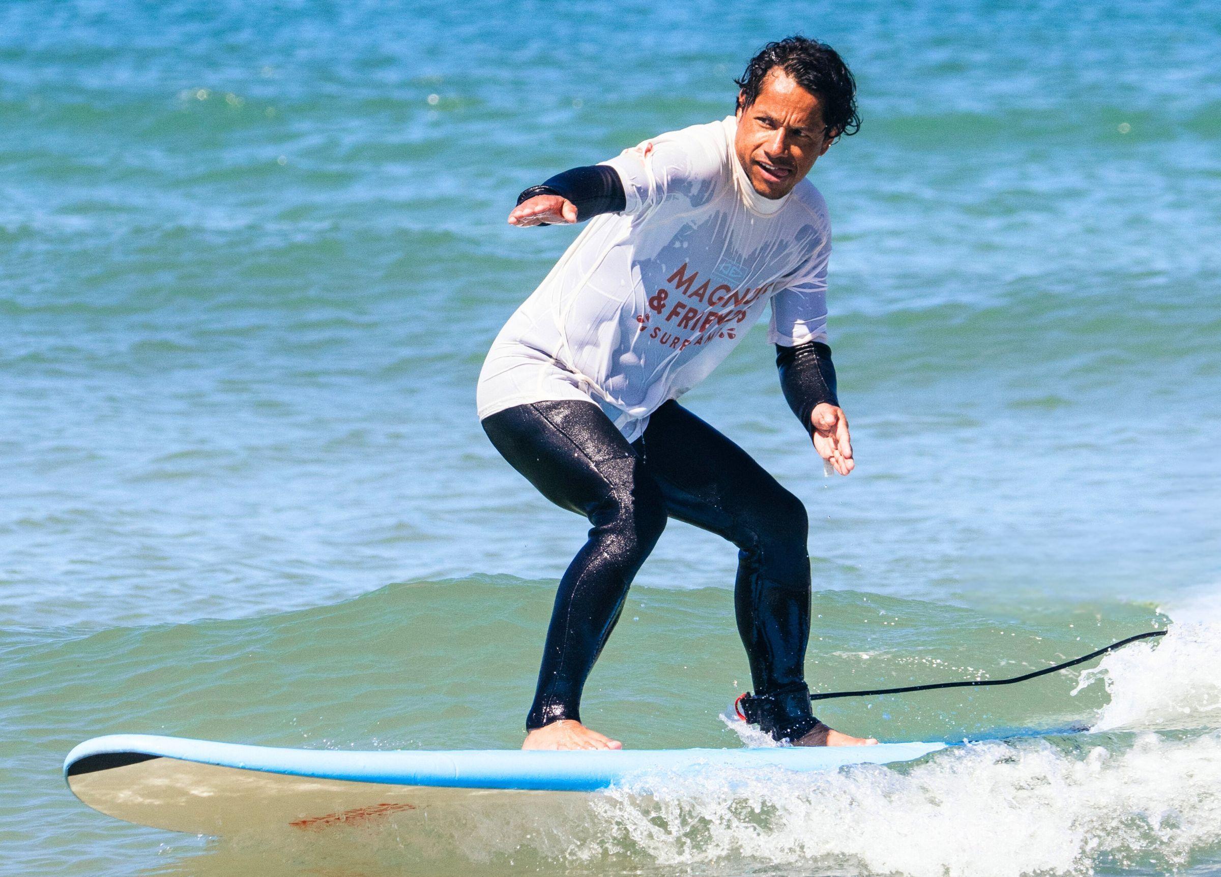 En surfare på en våg med en Magnus & friends-rashguard på