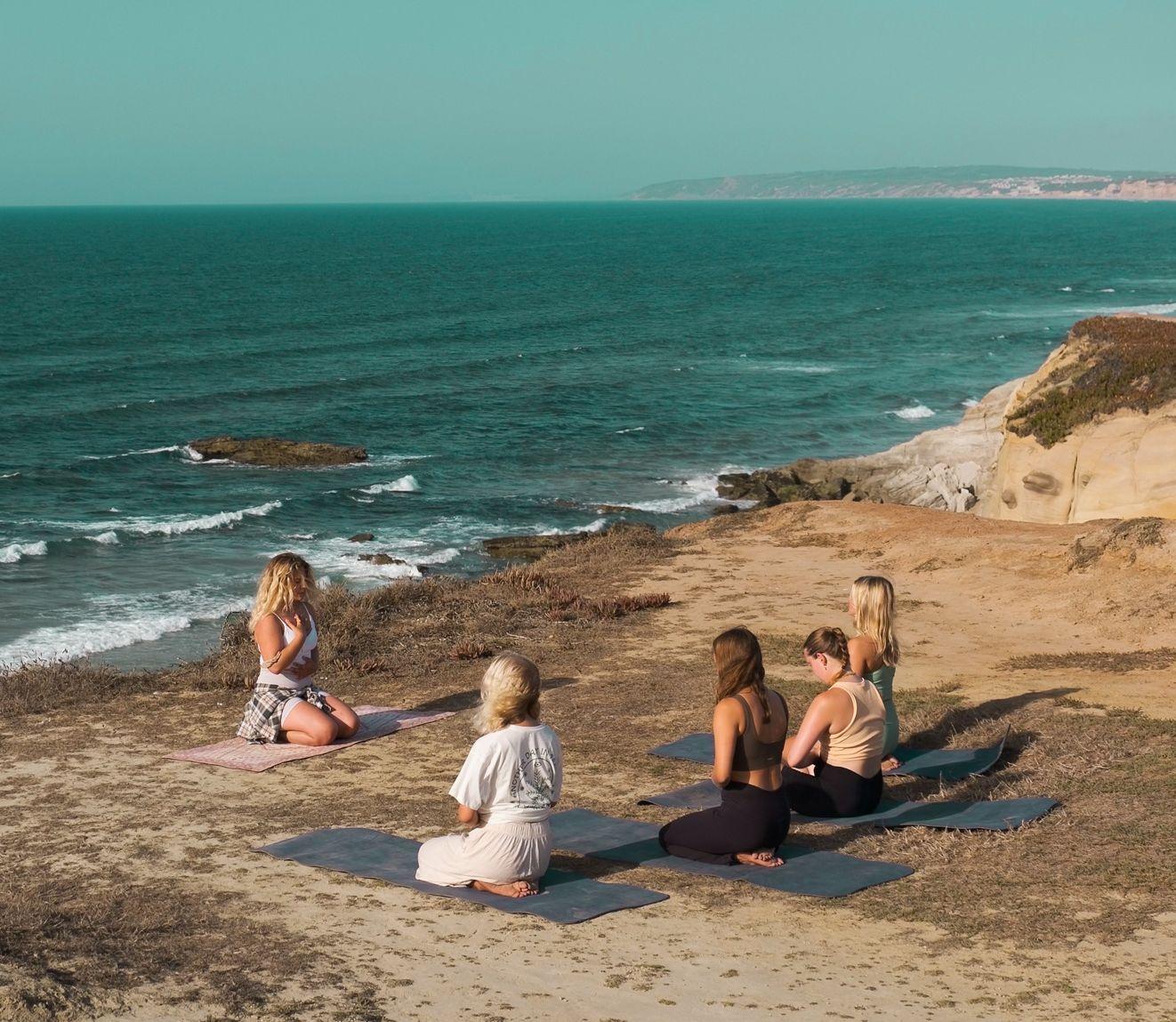 Tjejer som tränar yoga på klipporna